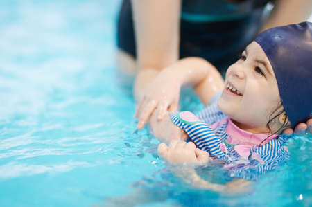 Happy kid learning to swim at school with teacher supportの写真素材