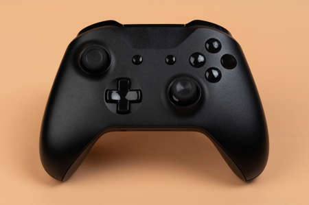 Black game controller front view isolated on brown backgroundの写真素材