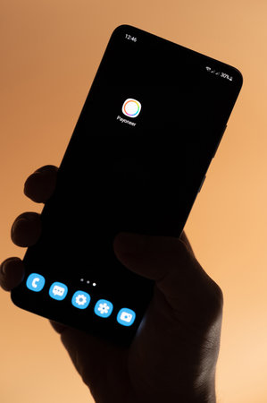 New york, USA - November 4, 2022: Open Payoneer app on smartphone holding in hand isolated on brown backgroundのeditorial素材
