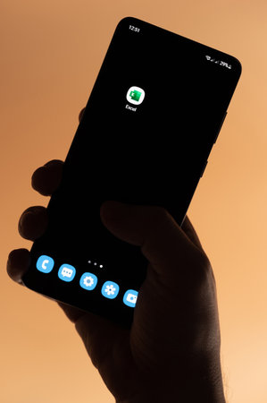 New york, USA - November 4, 2022: Open Microsoft excel app on smartphone holding in hand isolated on brown backgroundのeditorial素材