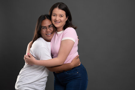 Two young hispanic people hug  on grey studio backgroundの写真素材