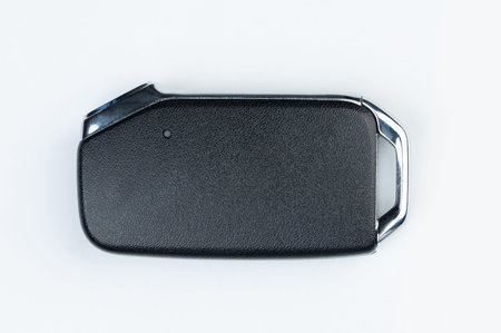 Black car key with metal frame isolated on white studio background close up view