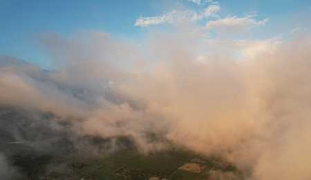 Fluffy clouds cover green landscape aerial drone viewの写真素材