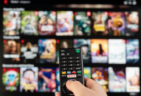 New york, USA - February 21, 2023: Select video on Netflix stream service on tv with remote control in handのeditorial素材