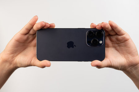 New york, USA - February 24, 2023: Purple iphone 14 pro max in hands back view with tripple camera set upのeditorial素材