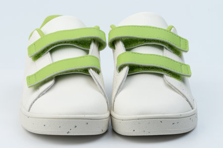 Pair of white child shoes with front view isolated on studio backgroundの写真素材