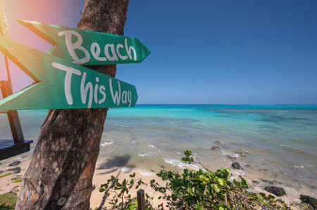 Wooden arrow sigh to beach on blue sea sky backgroundの写真素材