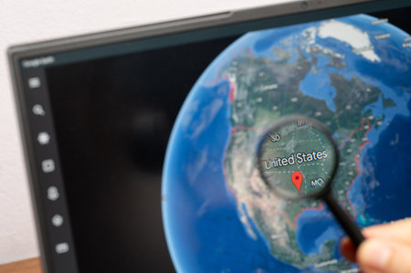 New York, USA - July 11, 2023: Zooming on United States country through magnifying glass on screen of google earth close up viewのeditorial素材