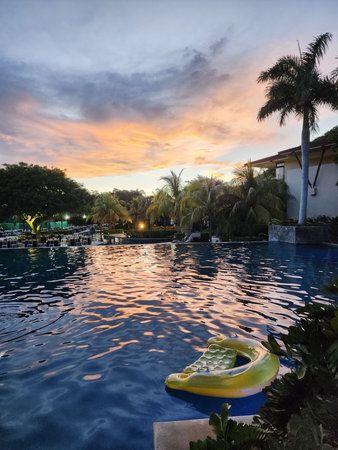 Swimming pool on sunset light in tropical resort background