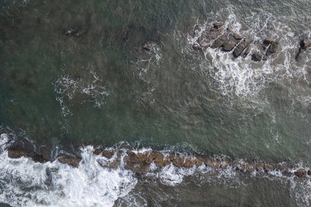 Green ocean wave hit brown rocks above top drone view