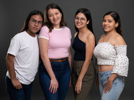 Four smiling latin american young people on grey studio backgroundの写真素材