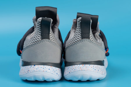 Kid gray running shoes back view isolated on blue studio background