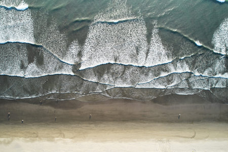 People enjoy sunset on ocean beach above top drone view