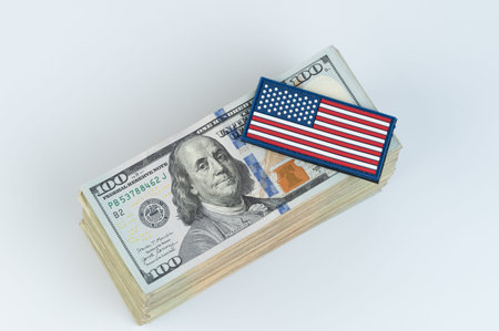 100 dollars bill pile with American flag sticker on top