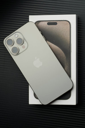 New York, USA - January 23, 2024: Gray natural titanium iphone 15 pro max lay on black table with...