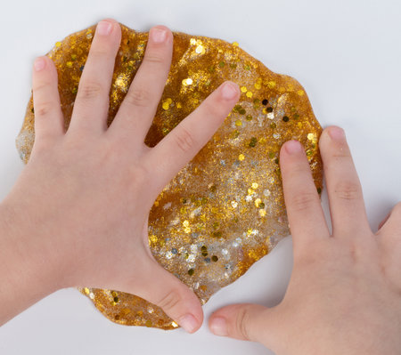 Kid play with gold color slime macro close up view isolatedの写真素材