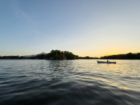Man in fishing boat in orange color sunset lightの写真素材