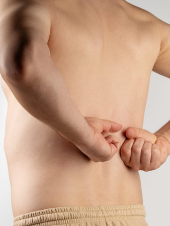 Man massaging his lower back himself isolated on white studio background