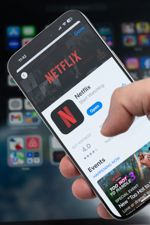 New York, USA - August 5, 2024: Smartphone in hand with Netflix app on screen macro close up view with blur backgroundのeditorial素材