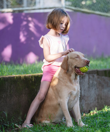 Kid girl playing with labrador dog outsideの写真素材