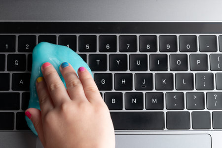Collecting dust from keyboard with colorful blue gel above top viewの写真素材