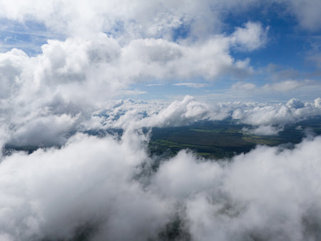 Breathtaking view of fluffy clouds above lush green fields under bright blue sky, showcasing nature's beauty.の写真素材