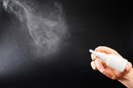 Flu home treatment theme. Nasal spray cloud isolated on black studio backgroundの写真素材