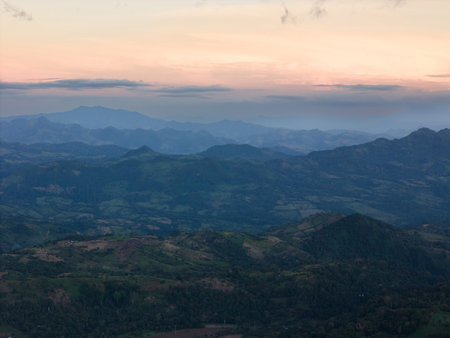 Many green hills landscape background in orange sunset light aerial viewの写真素材