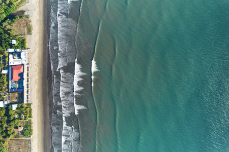 Turquoise color ocean surface with waves hits beach above top drone viewの写真素材