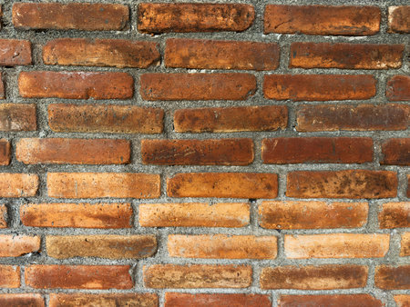 Close-up of rustic red brick wall featuring mix of textures and colors, highlighting craftsmanship in construction.の写真素材