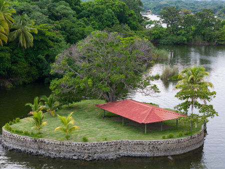 Empty small island with green grass and red roof building aerial viewの写真素材