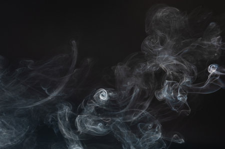 Smoke effect curve lines flow isolated on black studio backgroundの写真素材