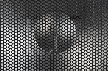 Circular speaker positioned behind perforated mesh, creating modern and stylish appearance in room.の写真素材