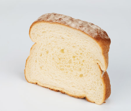 Slice of soft white bread displayed upright, showcasing its airy texture and golden crust, ideal for various meals.の写真素材