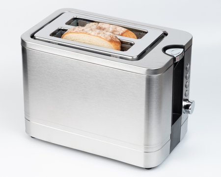 Sleek stainless steel toaster holds two slices of bread, waiting for perfect browning in modern kitchen.の写真素材