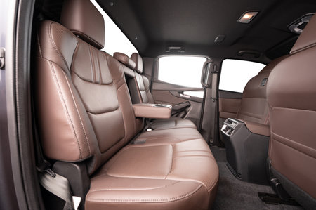 Comfortable rear leather seats and open cupholder in car interior with isolated windowsの写真素材