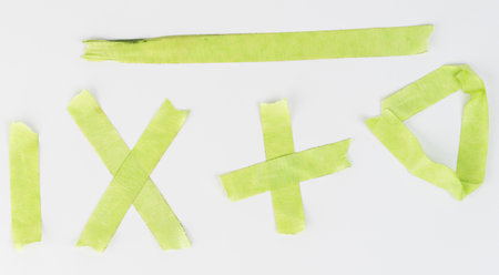 Variety of green tape pieces arranged on white background, creating different shapes and symbols under bright light.の写真素材