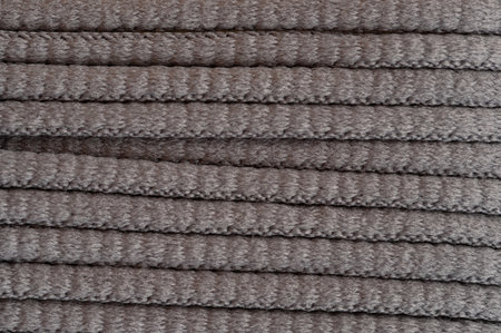 Soft grey fabric rolls neatly arranged on flat surface inside bright workshop, showcasing their texture.の写真素材