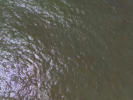 Brown ocean water surface with small waves above top drone view