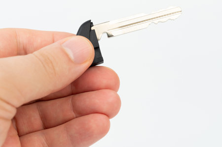 Small metal key in hand isolated on white studio backgroundの写真素材