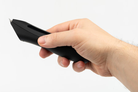 Hand grips black writing tool, highlighting its smooth curves and contemporary design in...
