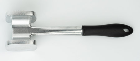 Sturdy metal mallet rests on white surface, ideal for tenderizing meat or crushing ingredients during food preparation.の写真素材