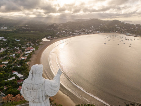 A stunning bay view set against a sunset, featuring a prominent statue. Boats float peacefully in the water as the sky glows.の写真素材