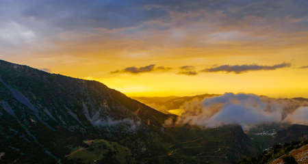Picturesque mountain valley filled with curly clouds at sunset.の写真素材