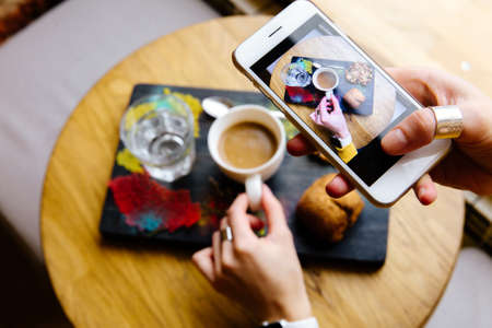 The girl in the restaurant photographing the food on the phone.の写真素材