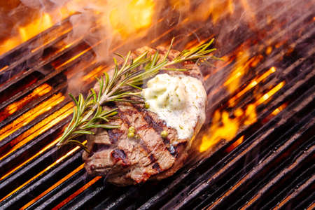 steak on a grill fire, with herbs and butterの写真素材