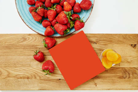 scattered strawberries on a wooden cutting boardの写真素材