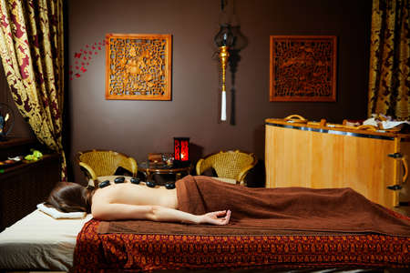 Closeup on young woman receiving hot stone massageの写真素材