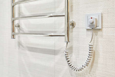 Modern heated towel rail on tiled socket bathroom wallの写真素材