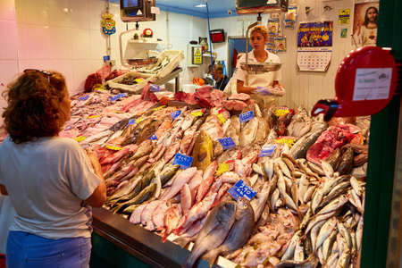 Valencia, Spain - October 23 2018: a stall holder discusses with a customer purchasing fish and seafood at the Central Marketのeditorial素材